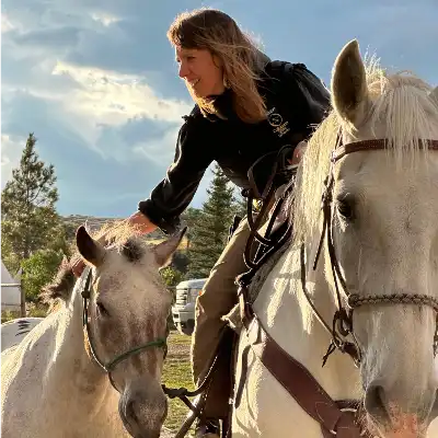 Photo of Dr. Anneke Johnson around two white horses